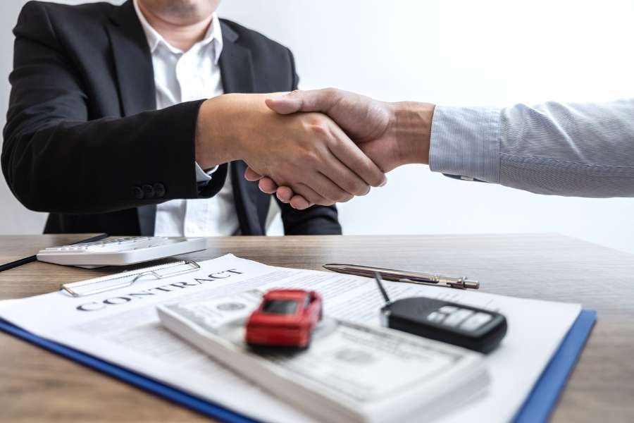 Signature d'un contrat d'achat avec un malus auto visible sur les documents.