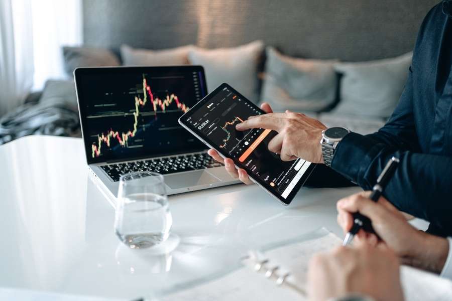 Un investisseur analyse des graphiques boursiers sur plusieurs écrans pour mieux diversifier les placements financiers.